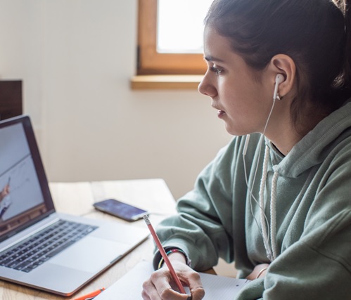 digital marketing photo - young woman with brown hair and green hoody with a laptop in front of her on a table