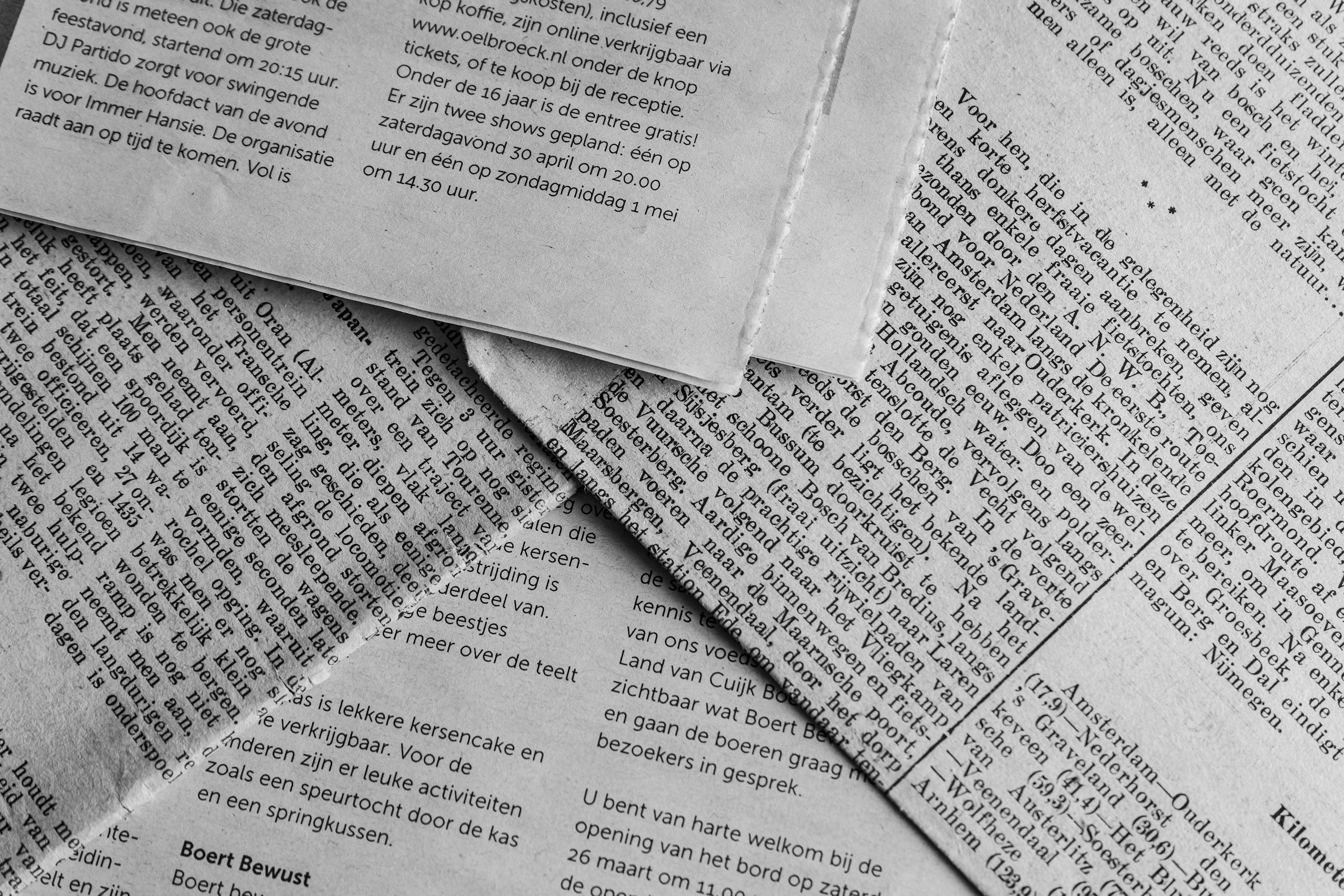 Black and white close-up of newspaper pages with text in Dutch.